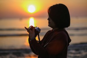 A silhouette of a photographer capturing the sunrise at the beach in Đà Nẵng, Vietnam.